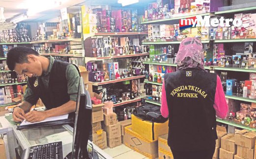 PEGAWAI penguat kuasa KPDNKK Kuala Lumpur memeriksa minyak wangi tiruan yang dirampas dalam serbuan di Chow Kit.