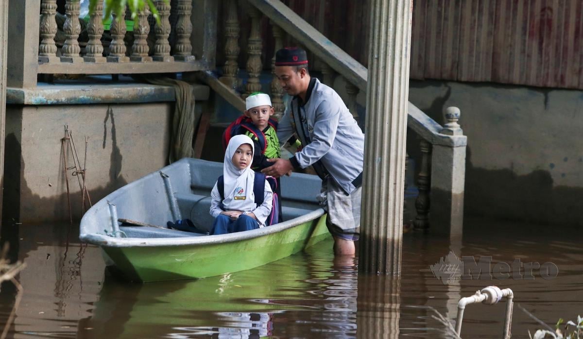 Mohd Irwan Faizal, 40 terpaksa menaiki bot membawa keluar untuk ke sekolah Kebangsaan (SK) Gual To deh susulan perkarangan rumahnya di genangi air banjir ketika ditemui di Kampung Tersang. FOTO NIK ABDULLAH NIK OMAR