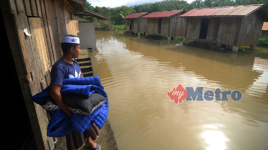 PELAJAR Madrasah Al-Imaniah Kampung Jerantut FerI menyelamatkan pakaian dan dokumen penting berikutan limpahan air sungai Pahang semakin meningkat. FOTO Nazirul Roselan