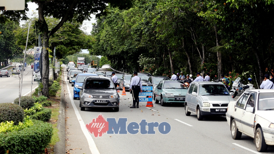 ANGGOTA polis memeriksa kenderaan pada sekatan jalan dalam Ops Bersepadu di Lebuh Alor Gajah-Melaka Tengah-Jasin (AMJ) berhampiran Melaka Sentral. FOTO Muhammad Zuhairi Zuber