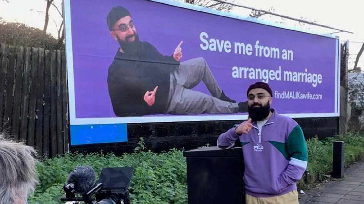MUHAMMAD Malik bersama papan iklan yang digunakan untuk mencari jodoh. Foto Instagram
