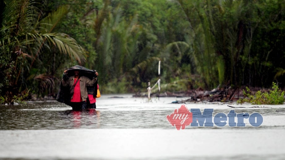 PENDUDUK Kampung Kalong terpaksa meredah air banjir selepas jalan utama ke kampung tersebut dinaiki air banjir di Sungai Miang. FOTO Farizul Hafiz Awang