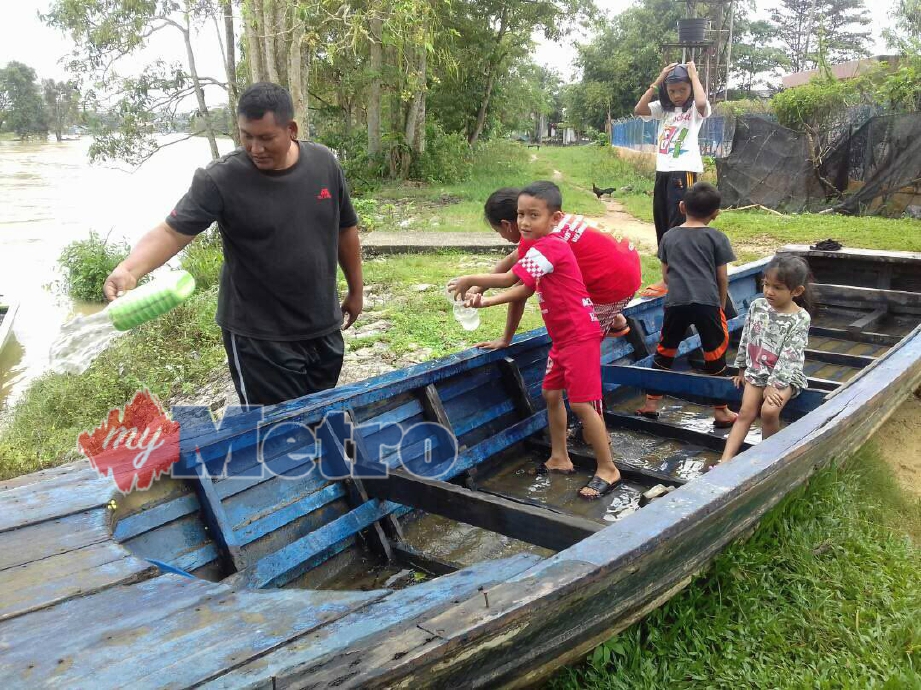 NIK Rodi Nik Soh, 41, membuang air yang bertakung di dalam botnya dibantu anak-anak, selain memastikan keadaannya baik untuk kegunaan ketika banjir. FOTO Syaherah Mustafa
