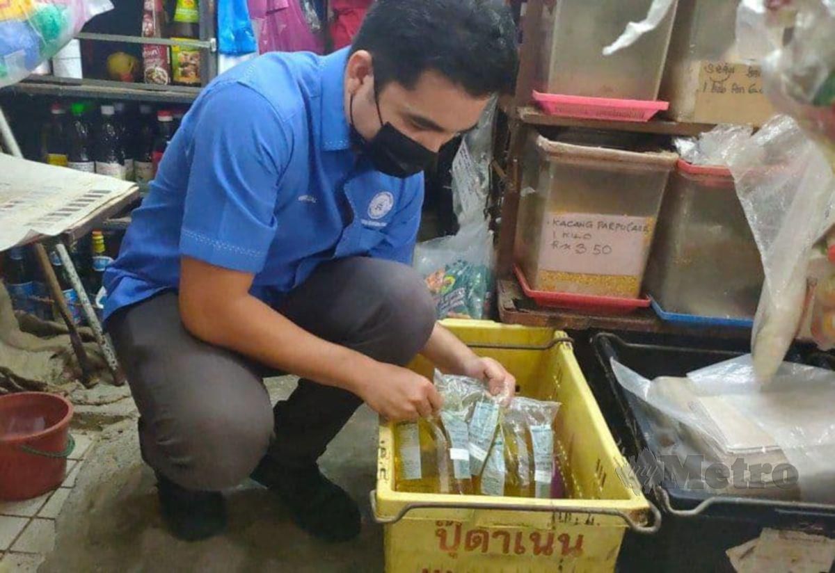 Setiausaha CAKE, Mohd Yusrizal Yusoff menunjukkan bekalan minyak masak yang berkurangan di kedai runcit di Pasar Besar Alor Setar. FOTO ZULIATY ZULKIFFLI