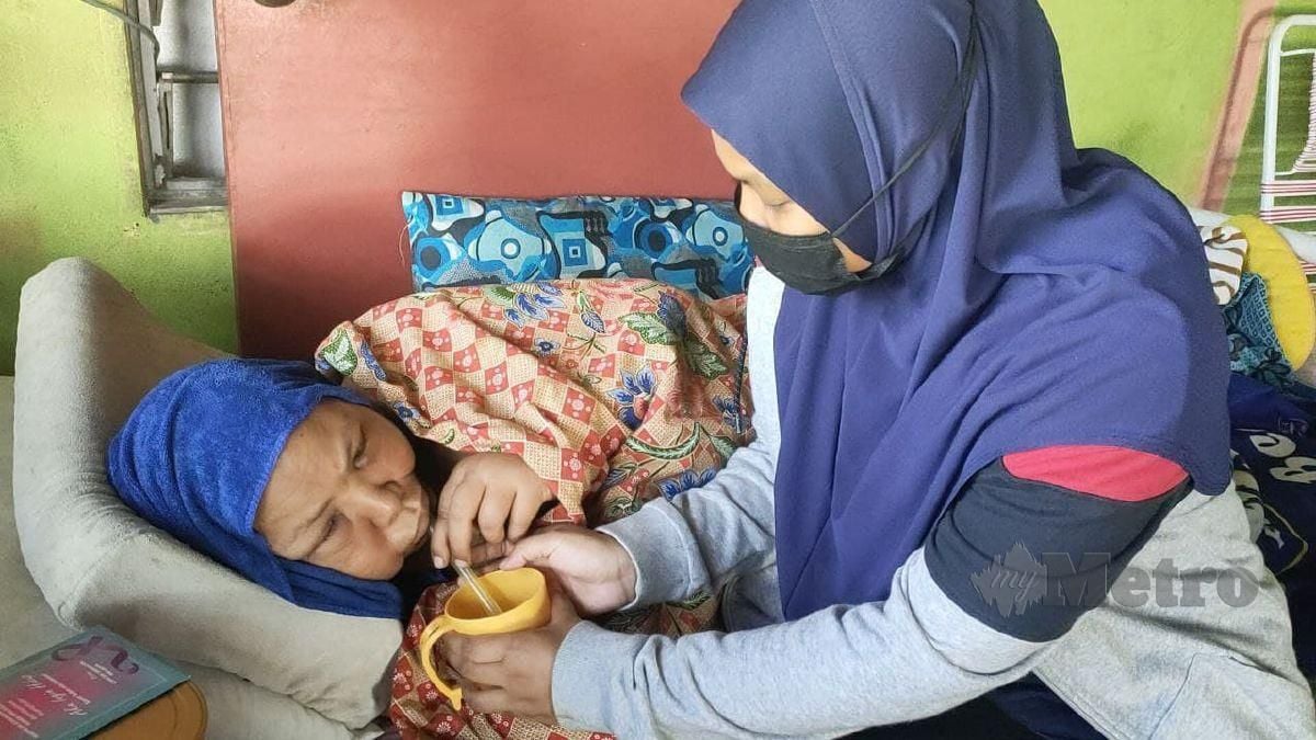 Nurul Syafiqah Che Din membantu menyuapkan minuman ke mulut ibunya, Siti Fatimah Hanafiah @ Omar, 52, yang menghidap kanser payudara tahap empat. FOTO ZULIATY ZULKIFFLI