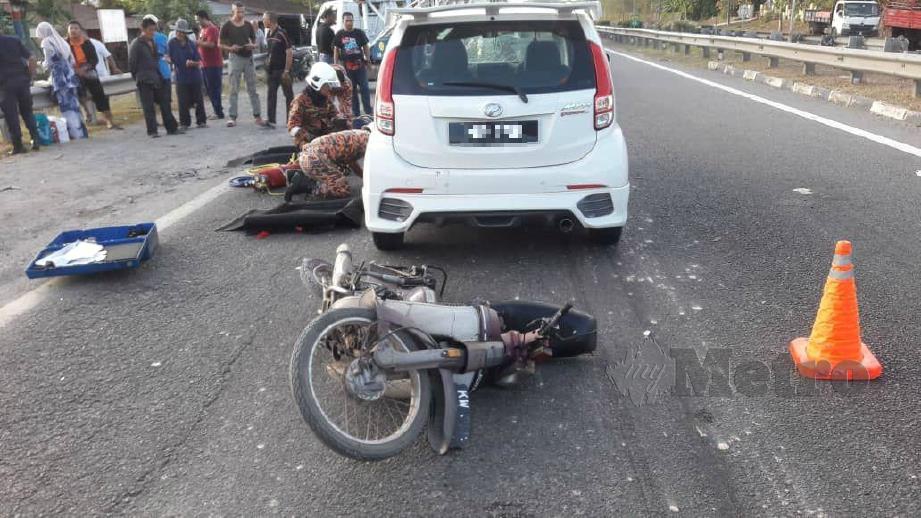 ANGGOTA bomba berusaha membantu mengeluarkan penunggang motosikal yang terperosok di bawah kereta Perodua Myvi dalam kemalangan di Kilometer 22 Lebuhraya Utara Selatan, arah selatan dekat Asun. FOTO Ihsan Pembaca