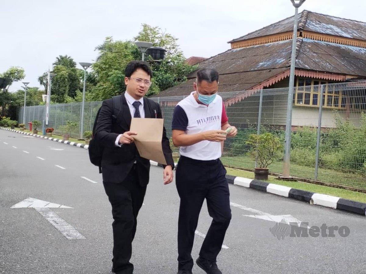 Tertuduh bersama peguam berjalan keluar daripada kawasan Kompleks Mahkamah Besut selepas selesai membayar denda. FOTO Nurul Fatihah Sulaini