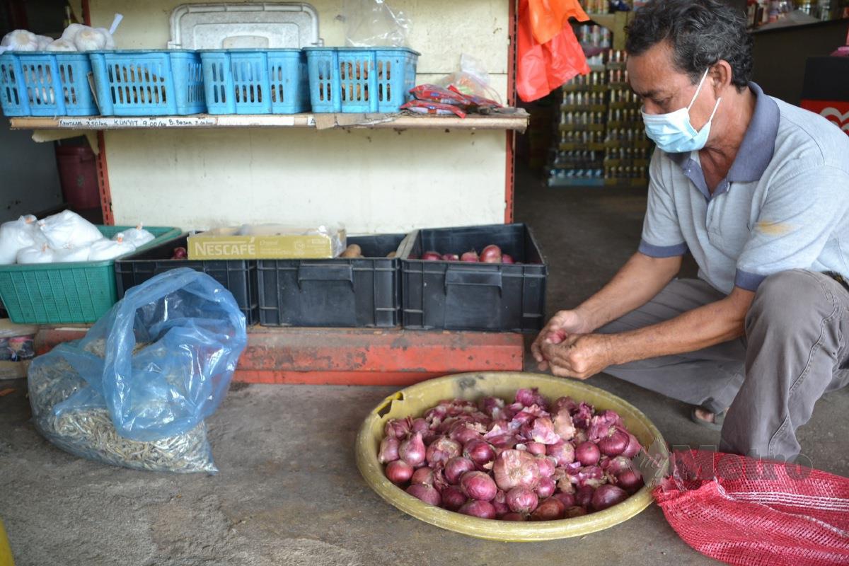 Shamsul mengupas kulit bawang di kedainya di Kampung Solok Duku, Masjid Tanah. FOTO Hassan Omar