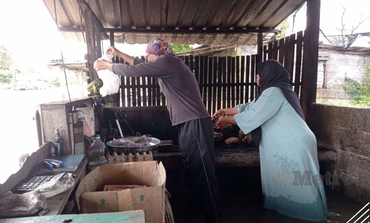 Peniaga bahulu bakar Rizal Mohamad, 51, dan isterinya, Rosnani Said, 51, melihat keadaan kedai mereka di Jalan Haji Ariffin, Endau, Mersing, Johor yang dinaiki air dalam tinjauan Bernama, semalam. FOTO BERNAMA