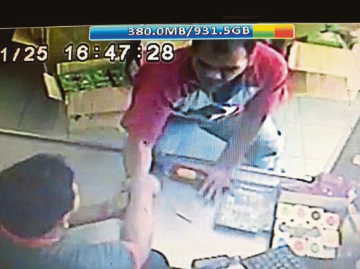 RAKAMAN CCTV menunjukkan penjaga kaunter menarik tangan pencuri yang cuba mencuri tabung derma. 