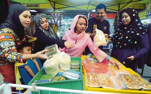  NATASHA (tengah) melayan pelanggan yang mahu membeli juadah berbuka puasa menerusi konsep menjaja dari kedai ke kedai.