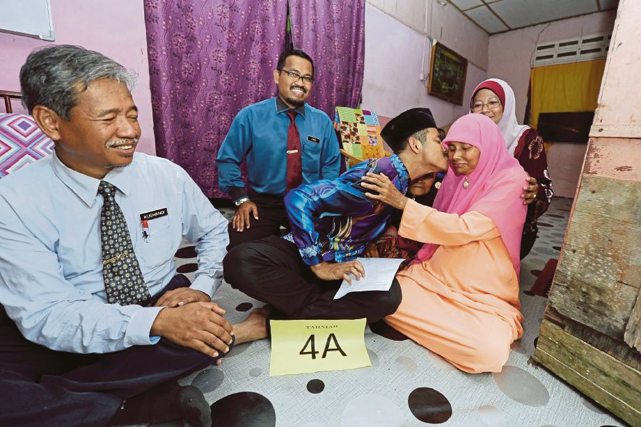 MUHAMMAD Amirul Aiman yang memperoleh PNGK 4.0 meraikannya dengan ibunya, Muniah serta gurunya..