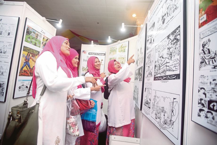 PEMERHATI Puteri UMNO melihat kartun yang dipamerkan pada Perhimpunan Agung UMNO  di PWTC, semalam.