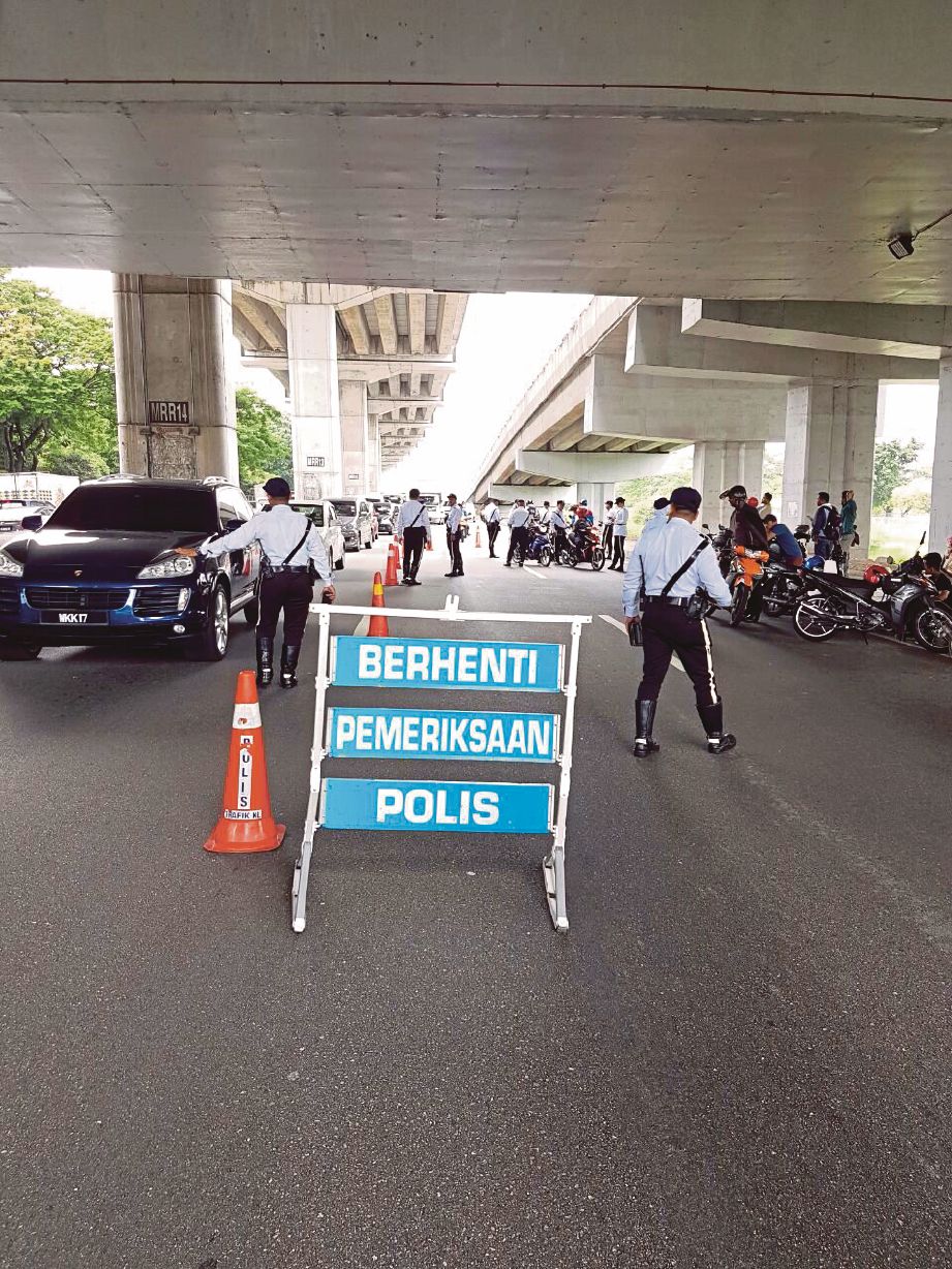Anggota polis trafik menjalankan pemeriksaan terhadap penunggang motosikal dalam Ops Warta di Jalan Shamelin.