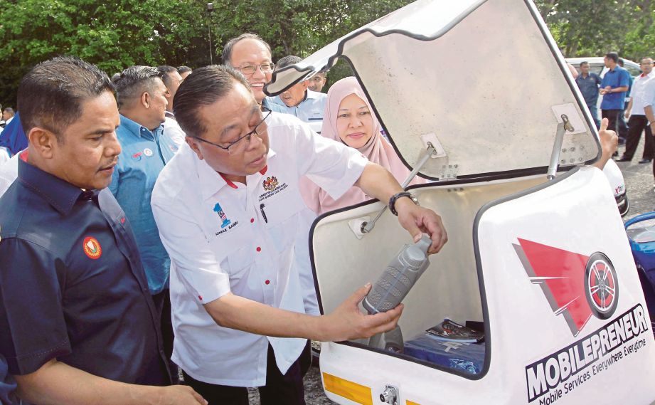 ISMAIL Sabri diiringi Pengerusi Jawatankuasa Penerangan, Pembangun Luar Bandar dan Pembasmian Kemiskinan Negeri Kedah Datuk Mohd Tajuddin Abdullah melihat kotak yang dipasang pada motosikal.