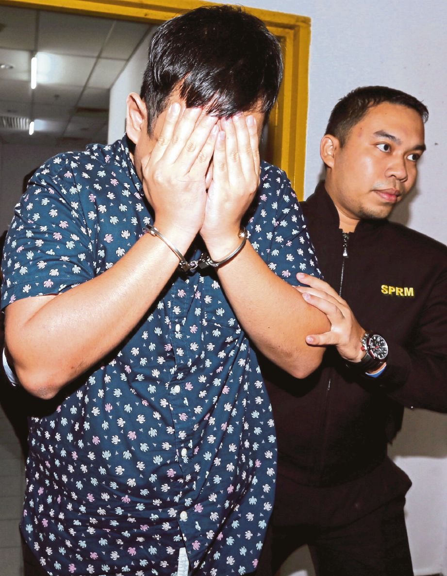 CHIN  Siang (kiri) menutup muka ketika dibawa keluar dari mahkamah, semalam.