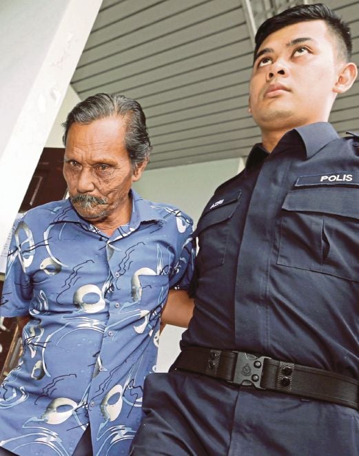 Hussin  diiringi polis selepas mendengar pertuduhan di Mahkamah Majistret, Melaka.