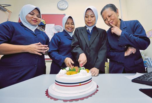  JULAIHA  (dua dari kanan) bersama rakan setugas memotong kek ketika menyambut hari lahirnya.