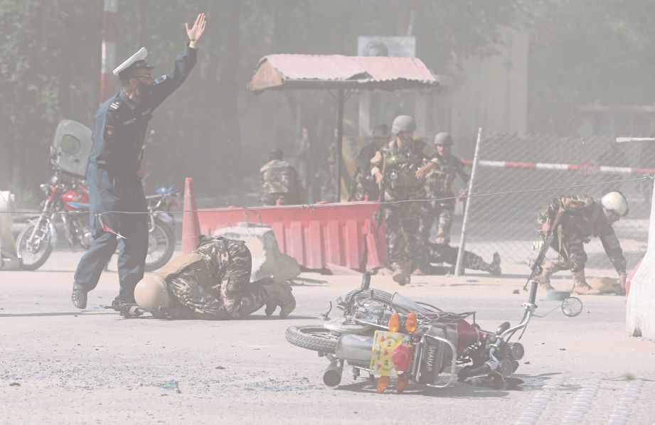 ANGGOTA keselamatan Afghanistan berlindung ketika seorang penyerang berani mati meletupkan dirinya. - Reuters