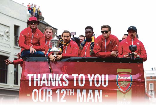 PEMAIN Arsenal berarak bersama trofi Piala FA di Kota London.