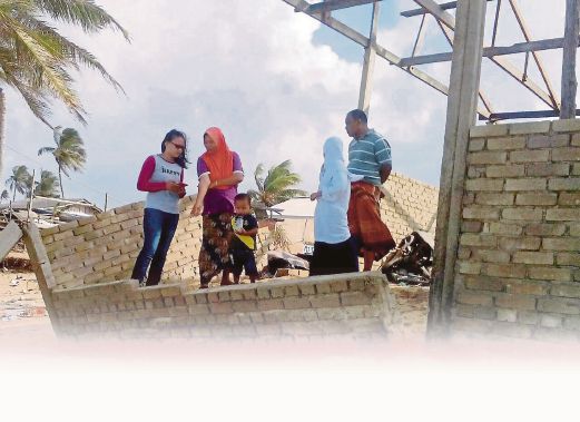 KAMARUDDIN bersama keluarganya  melihat sebahagian dinding rumah  mereka yang runtuh dibadai ombak.