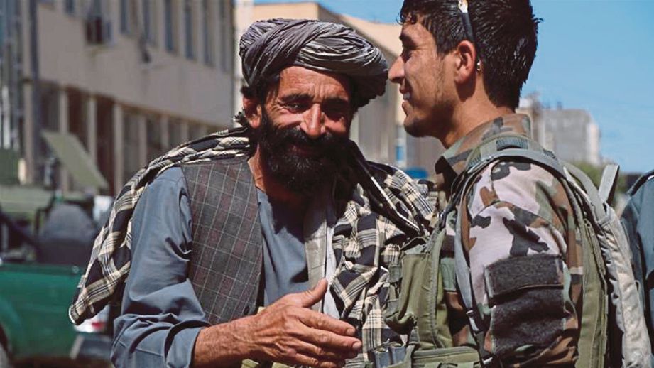 ANGGOTA Taliban bersalam dengan tentera Afghanistan di Herat ketika gencatan senjata sempena Aidilfitri. - Reuters