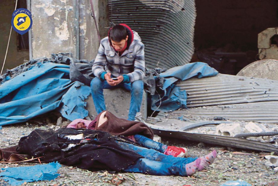 SEORANG remaja duduk di hadapan mayat mangsa serangan meriam tentera Syria di daerah Jub al-Qura di timur Aleppo, semalam.  - AP