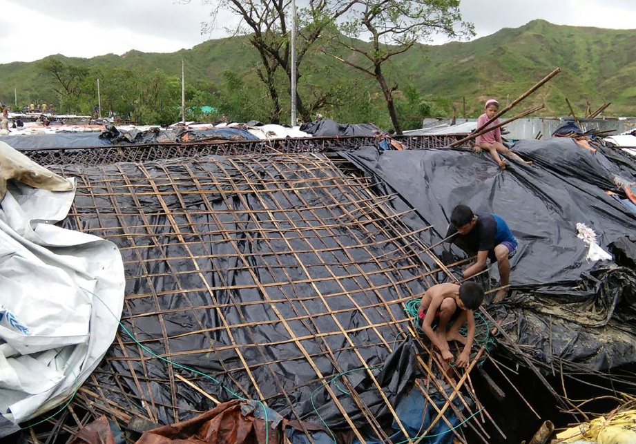 KANAK-KANAK pelarian Rohingya membetulkan bumbung khemah mereka di kem pelarian Cox’s Bazar selepas ia rosak selepas  puting-beliung Mora melanda daerah Bangladesh itu Isnin lalu.  -  AFP