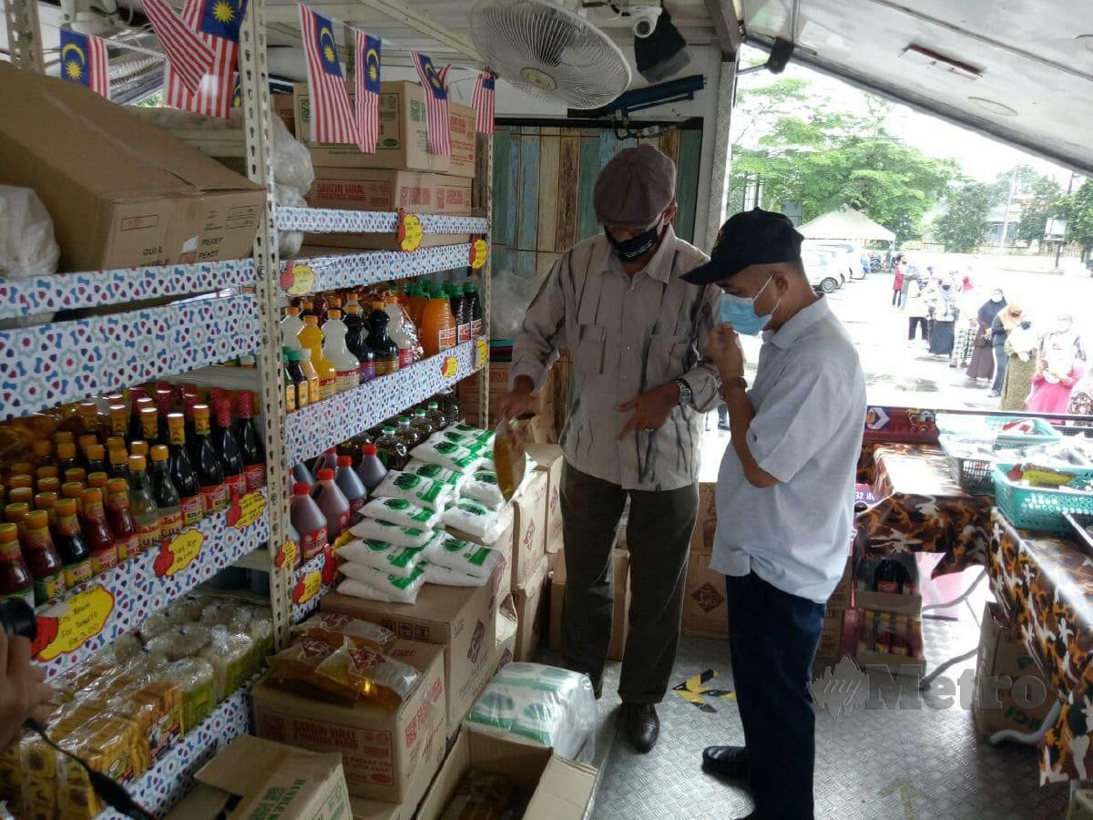 Rosol (kiri) sedang melayani pengunjung yang membeli belah barangan keperluan asas di Kedai Runcit Bergerak di Dataran Kuala Telemong, Kuala Berang, hari ini. FOTO BAHAROM BAKAR