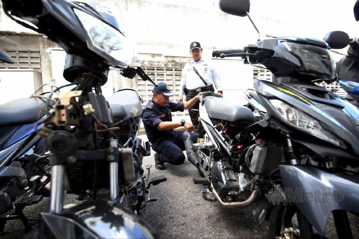 Pegawai Jabatan Pengangkutan Jalan (JPJ) dan anggota polis trafik menunjukkan motosikal yang diubah suai di sebuah bengkel motosikal dalam Ops Bengkel di sini, hari ini. FOTO MIKAIL ONG