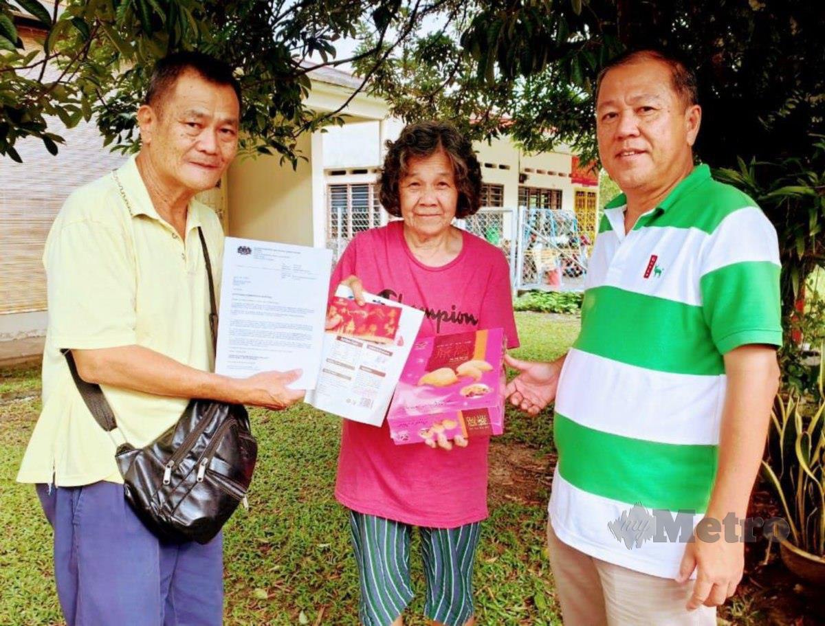 Yee Jee Kwong ( kiri) dan Wong Wing Yew ( kanan) menyampaikan surat kelulusan bantuan kewangan daripada JKM Daerah Batang Padang dan bantuan makanan serta wang daripada syarikat perumahan kepada Liew Yat Yong (tengah) di Kampung Baru, Bidor, hari ini. FOTO ROSMAN SHAMSUDIN
