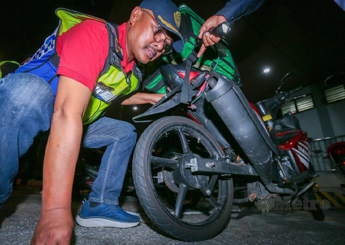 Pengarah Jabatan Pengangkutan Jalan (JPJ) Pulau Pinang Zulkifly Ismail menunjukkan motosikal yang digunakan seorang lelaki untuk perkhidmatan p-hailing telah diubahsuai termasuk tiada brek belakang ketika pemeriksaan dalam Ops Motosikal di Plaza Tol Pulau Pinang. FOTO DANIAL SAAD