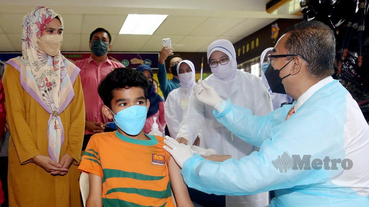 Timbalan Menteri Kesihatan, Datuk Dr Nooor Azmi Ghazali (kanan) menunjukkan picagari yang telah kosong kepada Azah Zainul, 41, (kiri) selepas memberikan suntikan vaksin kepada adik Nur Adib Darwisy Nordin, 12, ketika lawatan sempena Program Imunisasi Covid-19 Kanak-kanak (PICKids) di Pusat Pemberian Vaksin (PPV) Sekolah Kebangsaan (SK) Saujana Indah di sini. FOTO DANIAL SAAD