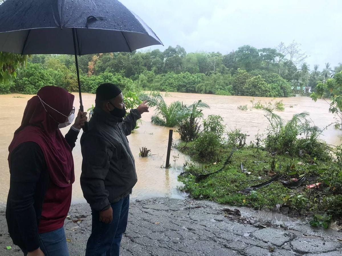 Penghulu Mukim Kuala Pertang, Mat Ropi Abdullah (kanan) menunjukkan jambatan Tanjung Kala yang ditenggelami air sejak pagi Jumaat lalu susulan hujan lebat berterusan sehingga menenggelamkan jambatan berkenaan. FOTO HAZIRA AHMAD ZAIDI