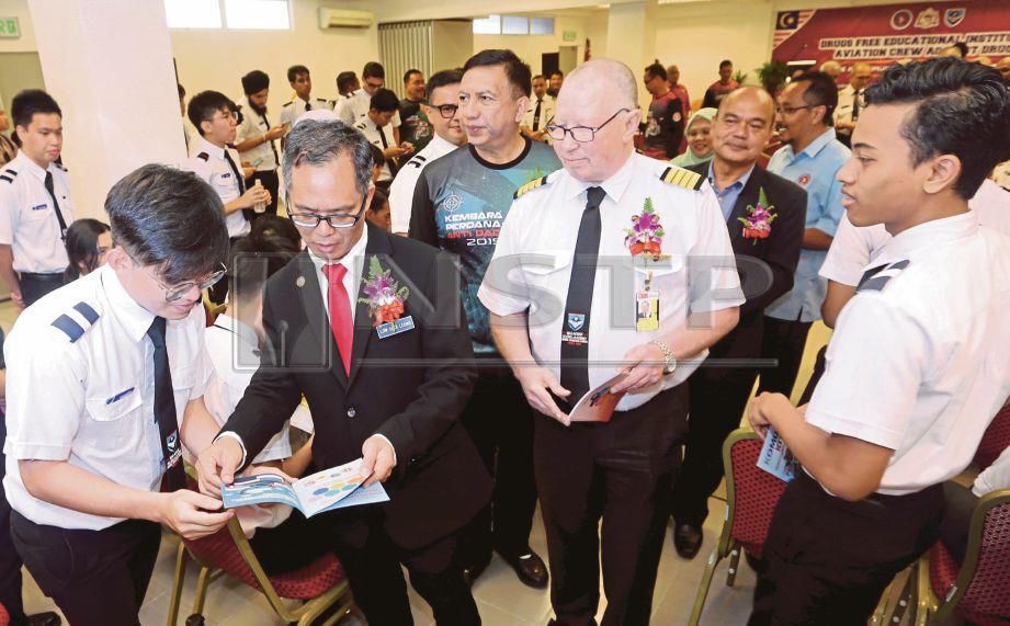 Chee Leong (dua dari kiri) menyampaikan risalah mengenai dadah kepada kadet penerbangan sambil diiringi Zulkifli (tengah) di Malaysia Flying Academy, Batu Berendam. FOTO Rasul Azli Samad
