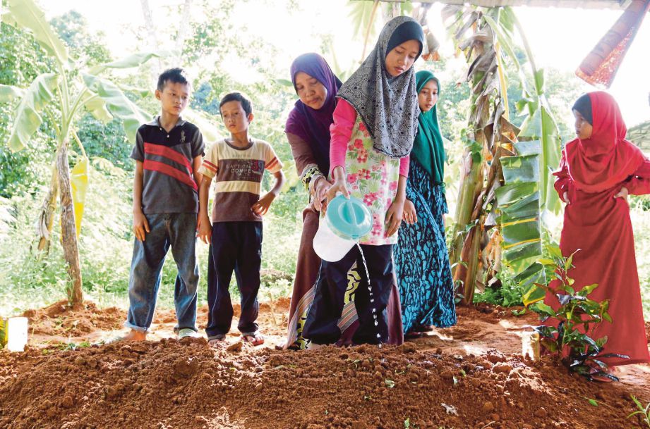  ANAK arwah, Siti Nor Zullaikha menyiram air mawar ke atas pusara ayahnya sambil  disaksikan adiknya, Mohd Faizal (kiri) dan Mohd Fakrullah  8, (dua dari kiri).