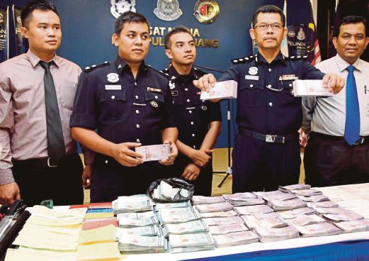 AZMI (dua dari kanan) menunjukkan sebahagian wang dirampas, di IPK Pulau Pinang, semalam.