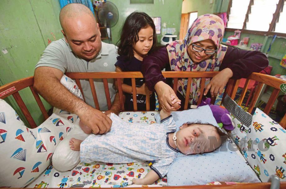 SHARIFAH Norlita bersama suami Iskandar Dzulkarnain Amlan dan anaknya Maryam Dafiya, 6 melihat anak keduanya, Yusuf Haris, yang menghidap sakit kronik ketika temui di Pekan. FOTO Muhammad Asyraf Sawal
