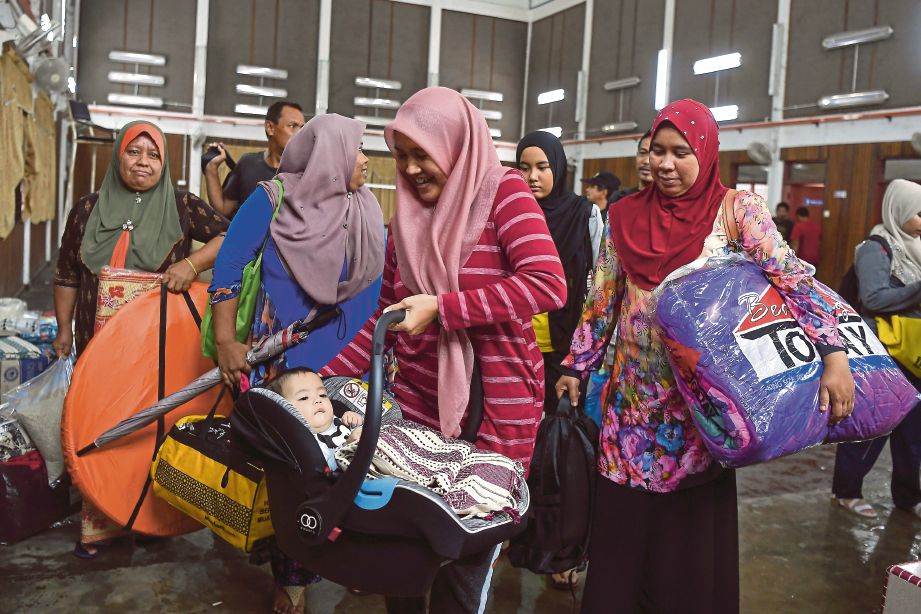 ROSLIZA membawa anaknya, Wan Ielias Danial bersama mangsa banjir lain berpindah ke PPS Sekolah Kebangsaan Kampung Amer selepas kemudahan PPS Dewan Sivik Alor Lintang tidak mencukupi. FOTO Bernama