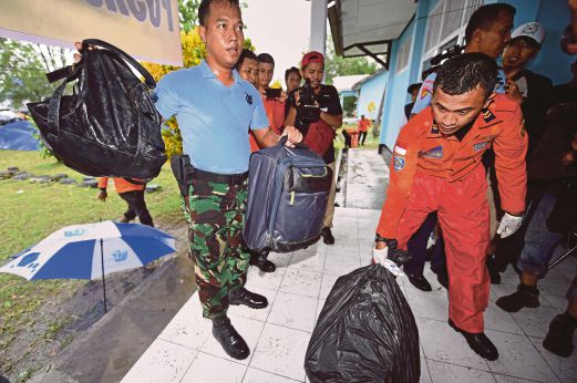 ANGGOTA tentera Indonesia (kiri) dan pasukan penyelamat tiba bersama barang milik penumpang penerbangan QZ8501 di Pangkalan Bun, semalam.