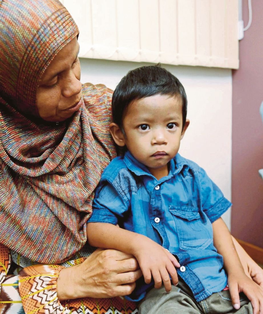  Siti Aminah memangku  Muhammad Haris yang menghidap jantung berlubang sejak lahir.