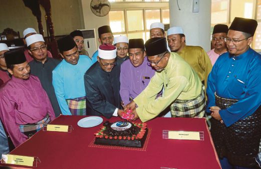 RAZALI (tengah) memotong kek sambil diperhatikan  Pengarah Darul Quran JAKIM, Zabidi Nasan (kanan).   