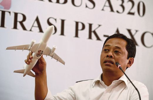NURCAHYO memegang model pesawat bagi menunjukkan bagaimana pesawat QZ8501 terhempas dalam satu sidang akhbar di Jakarta, semalam.