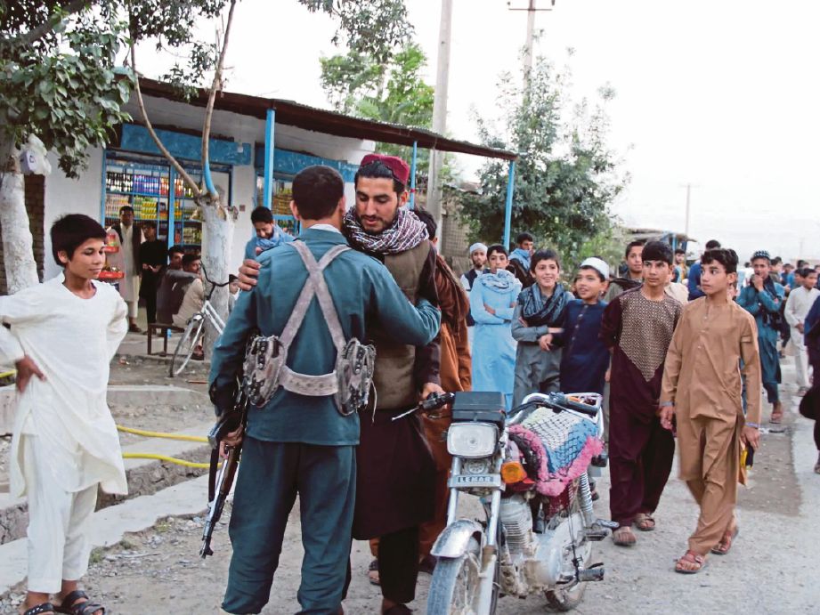 MILITAN Taliban dan tentera kerajaan Afghanistan bersalaman di Kabul ketika gencatan senjata tiga hari sempena Aidilfitri tahun lalu. FOTO EPA