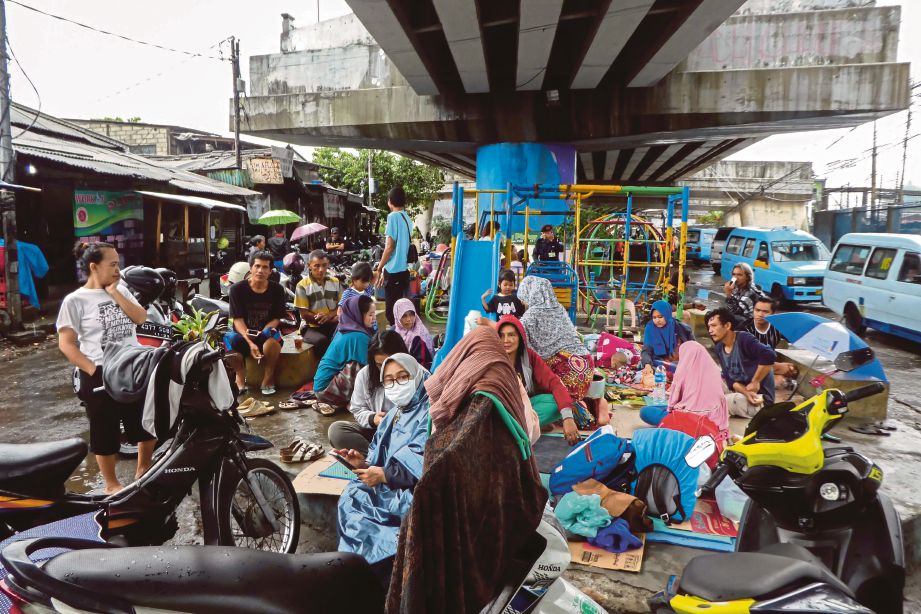 ORANG ramai berlindung di bawah jambatan selepas hujan sepanjang malam menyebabkan banjir  di beberapa daerah di Jakarta. - AFP