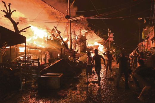 PENDUDUK di kawasan setinggan di Manila berusaha memadamkan kebakaran yang berpunca daripada pembakaran bunga api, awal semalam. 