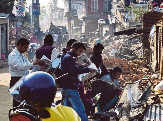PENDUDUK Kathmandu membaca akhbar apabila kehidupan semakin kembali normal.
