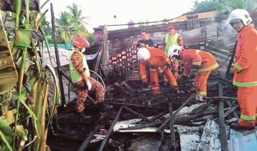 Anggota bomba mencari cebisan mayat Lumilis yang rentung di atas katil dalam kebakaran di Lorong Bambasang, Kampung Likas, Kota Kinabalu.