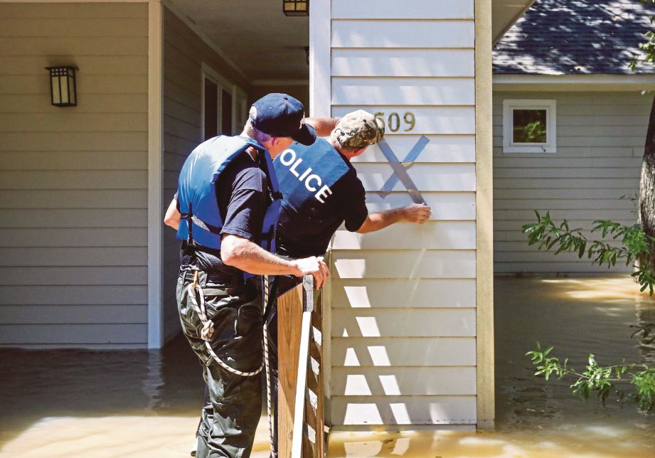 ANGGOTA polis menandakan rumah yang disahkan kosong dalam gerakan mencari mangsa di Houston. - EPA 