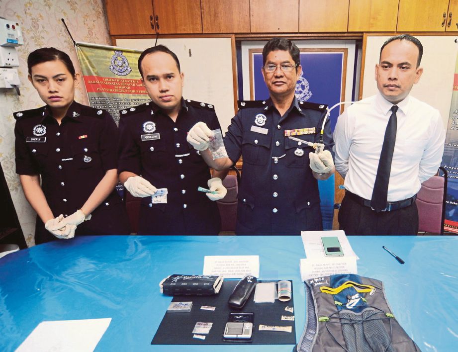 ZAINAL  (dua dari kanan) menunjukkan dadah  serta peralatan menghisap dadah yang  dirampas.